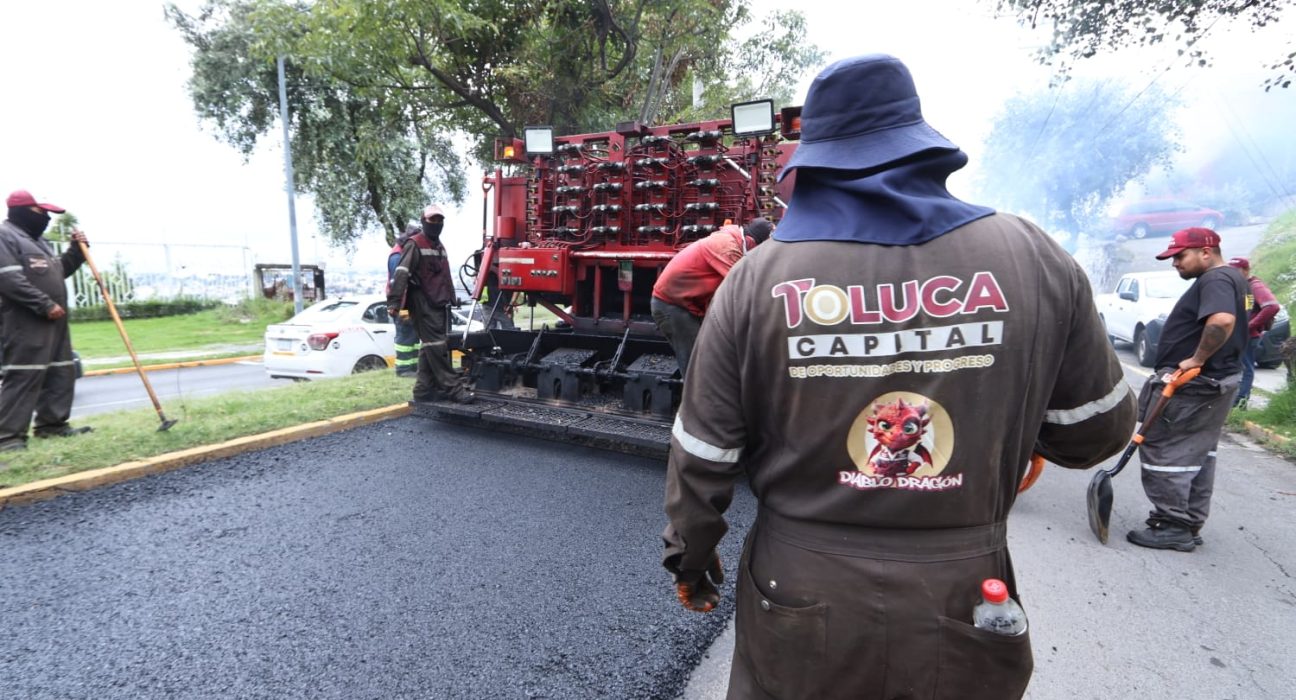 Trabajadores de Toluca operan la maquinaria del Diablo Dragón mientras pavimentan una calle.