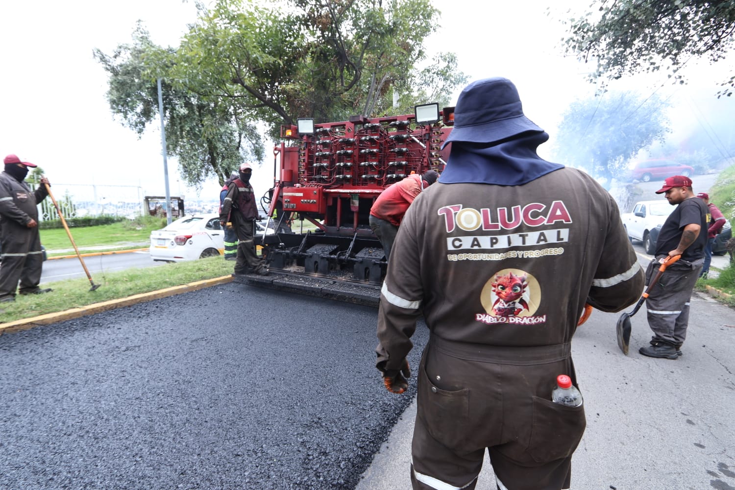 Trabajadores de Toluca operan la maquinaria del Diablo Dragón mientras pavimentan una calle.